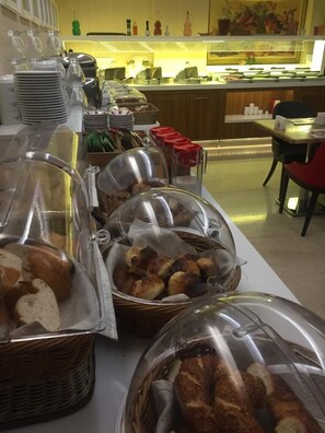 A buffet area with covered food displays, including bread and pastries, and a counter with various condiments and utensils. - Imamoglu Pasa Hotel - Boutique Class (Kocasinan)
