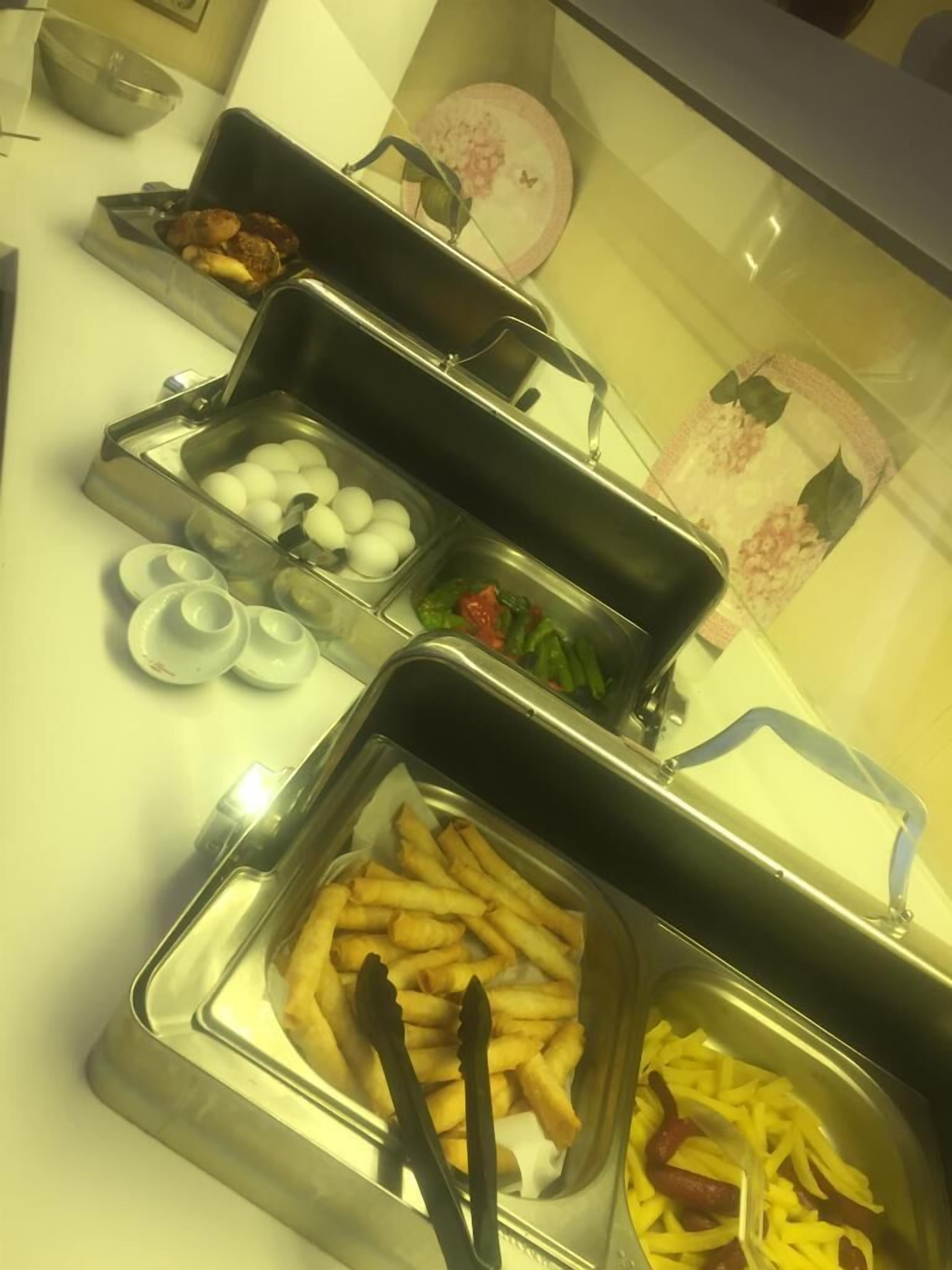 A buffet with various food items including eggs, vegetables, and French fries.