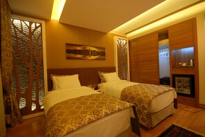 A hotel room with two beds, a painting on the wall, a wooden cabinet, and a small television. - Imamoglu Pasa Hotel - Boutique Class (Kocasinan)