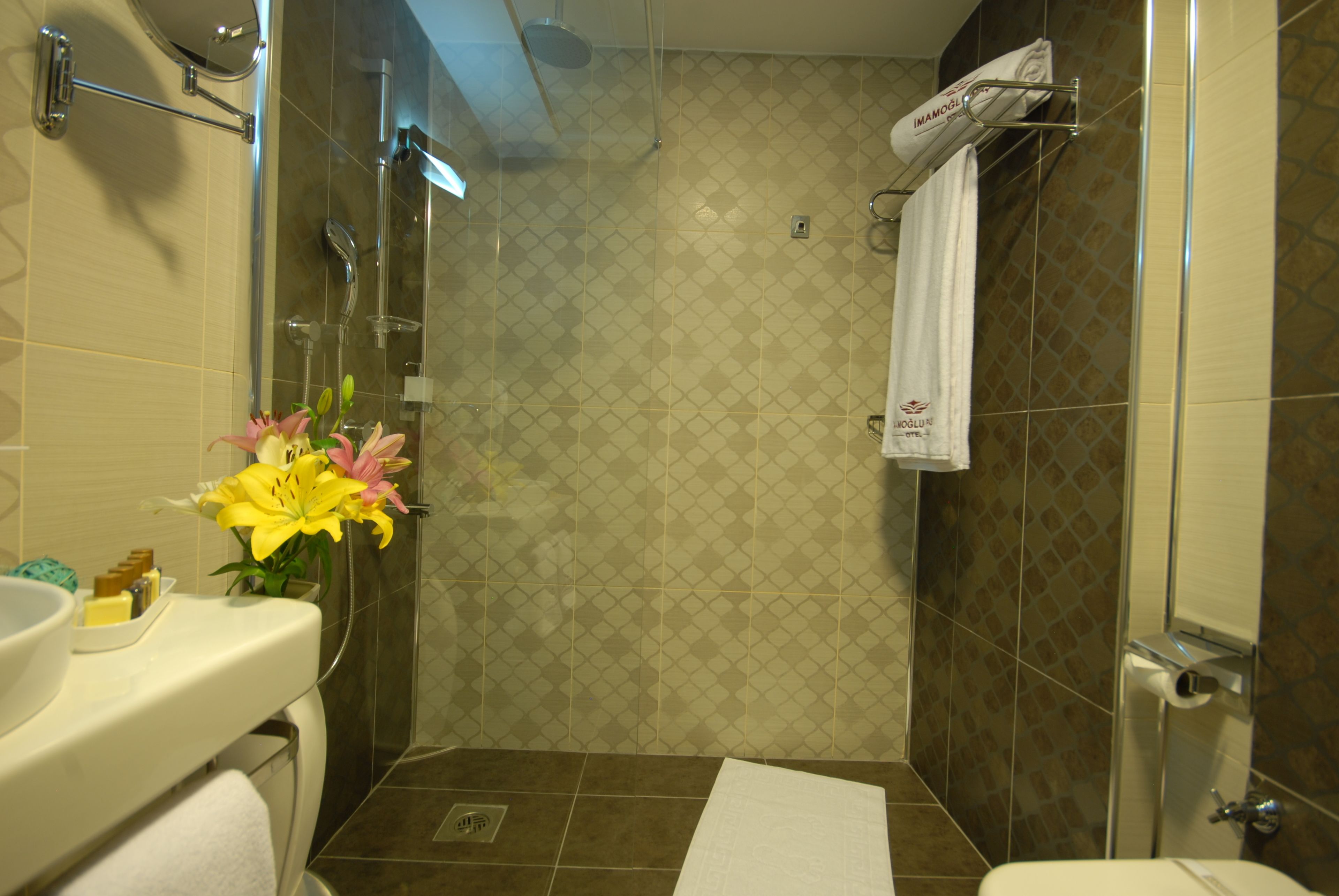 Une salle de bain avec une douche, un lavabo et des toilettes. On y trouve un porte-serviettes sur lequel est accrochée une serviette.