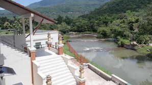 Un edificio con una escalera que conduce a una zona cubierta con vistas a un río y colinas boscosas.