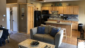 A cozy living room with a sofa and coffee table, wooden cabinets, a kitchen with a stone backsplash, and a sign reading "Carefree DR N97".