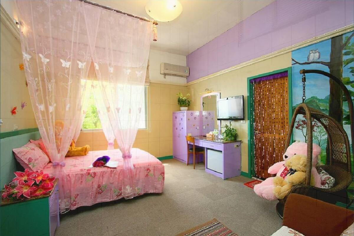 A bedroom with a bed, a desk, a chair, and a hanging chair with a teddy bear.