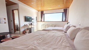 Une chambre avec un grand lit, un bureau, une télévision et une fenêtre avec des rideaux.