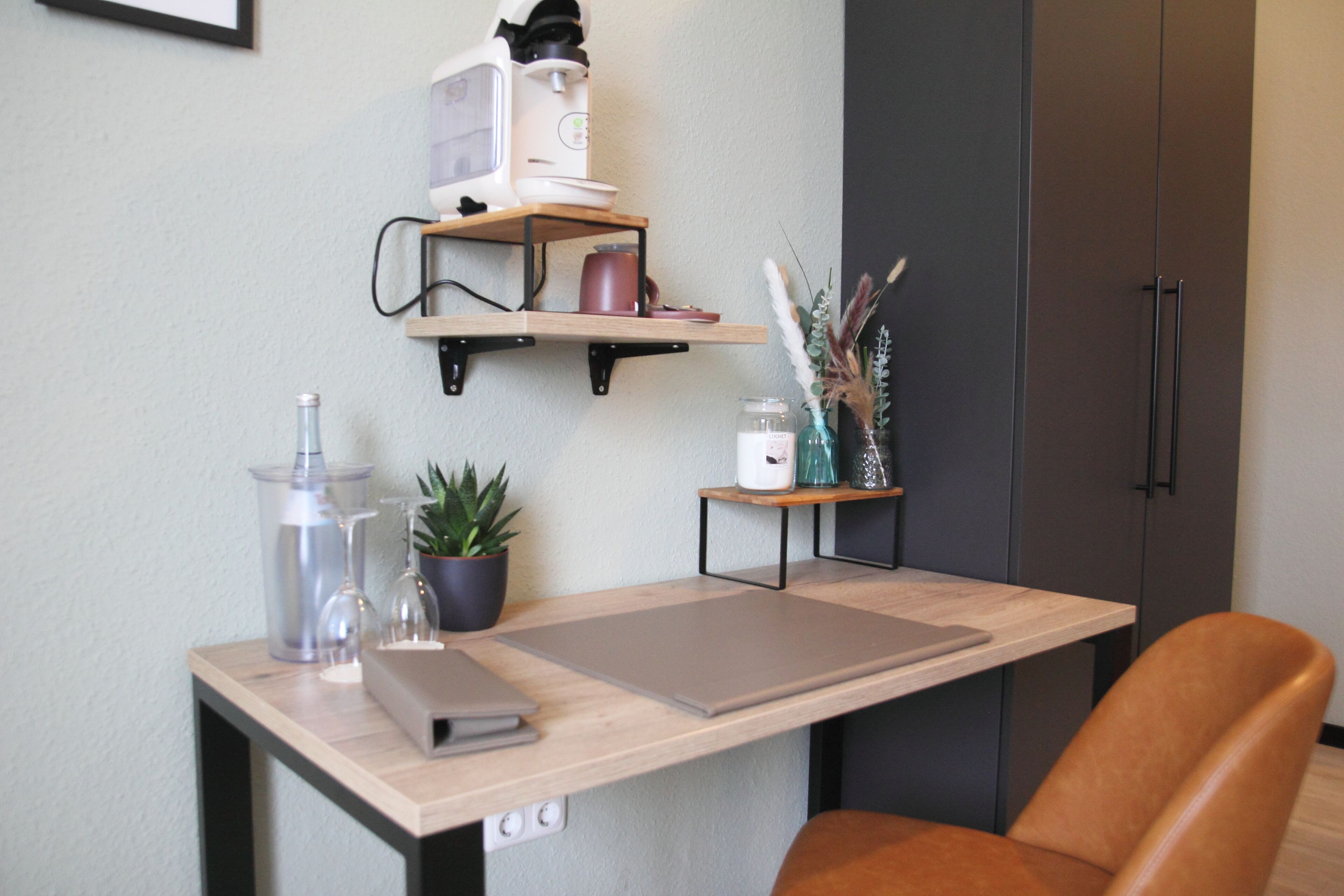 Eine moderne Küche mit Holzarbeitsplatte, einer integrierten Kaffeemaschine, einem Regal mit Küchenutensilien und einem Blumentopf.