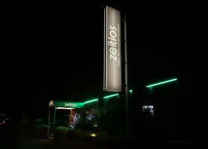 A hotel sign with the name 'Zeitlos' and a vertical sign for 'Hotel & Restaurant am Fuchsbach'. - zeitlos -  Hotel & Restaurant am Fuchsbach (Pattensen)