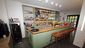 A bar area with a green bar counter, multiple stools, and shelves stocked with bottles and glasses. - zeitlos -  Hotel & Restaurant am Fuchsbach (Pattensen)