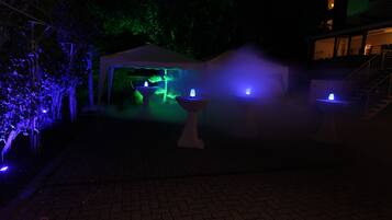 Un espacio al aire libre con carpas, una fuente e iluminación ambiental.