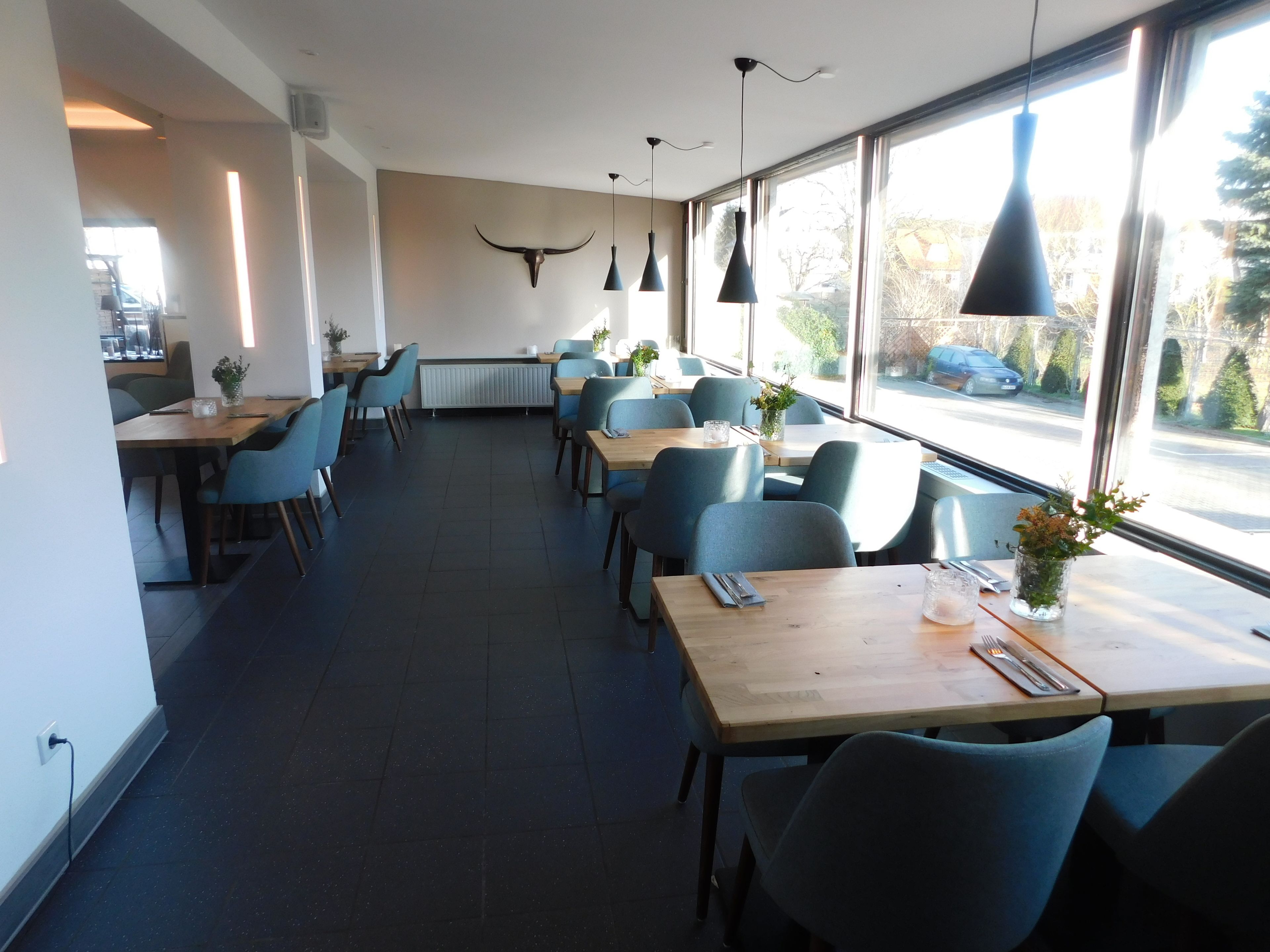 A restaurant with a long counter, blue chairs, and pendant lights.