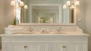 A bathroom with a large mirror, two sinks, and a chandelier.