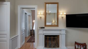 A hotel lobby with a fireplace, a large mirror, wall sconces, and a flat-screen TV.