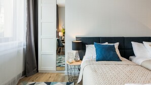 Une chambre d’hôtel avec un lit, une table de chevet avec une lampe, une chaise et une vue sur le couloir.