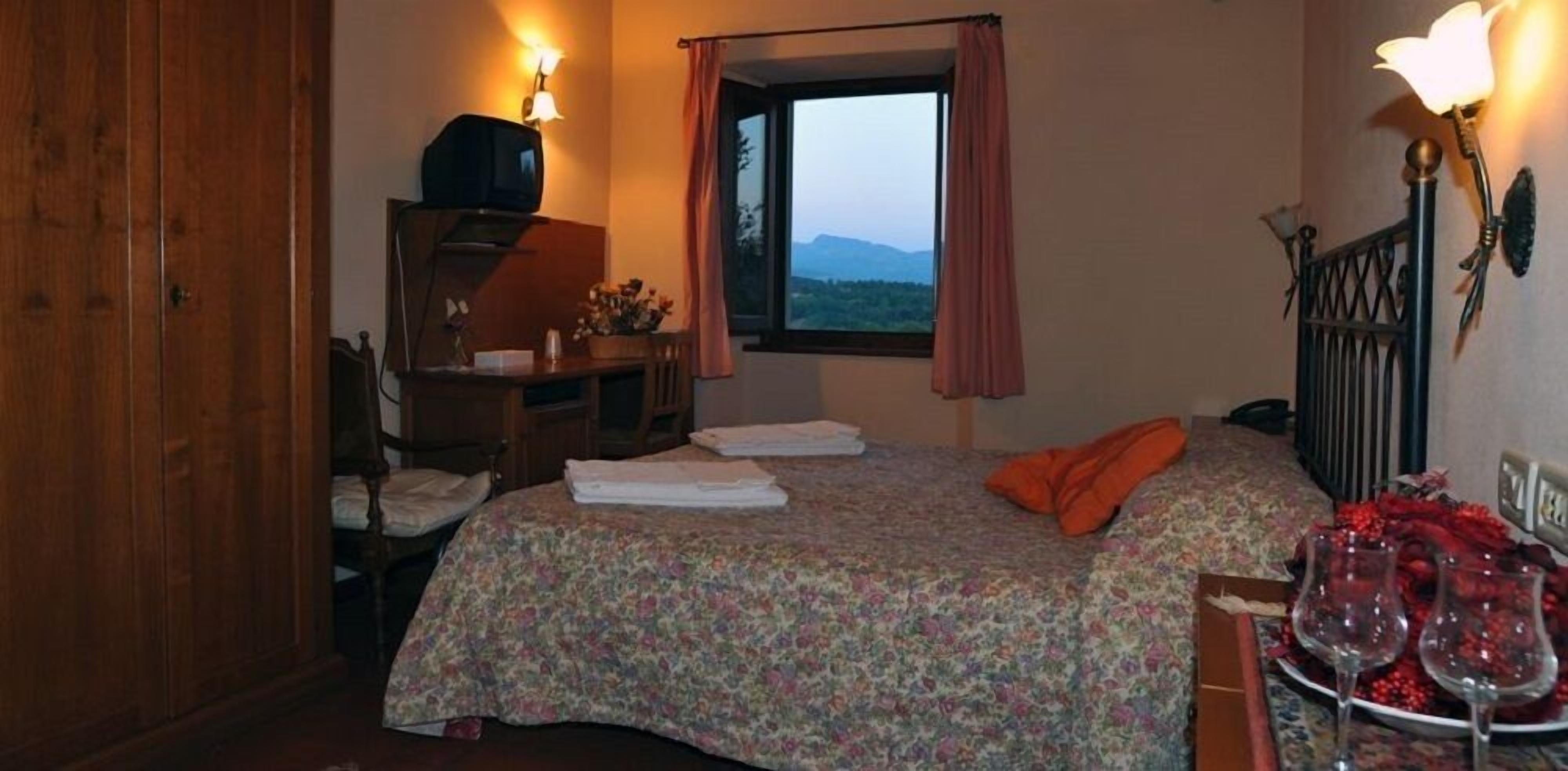 Un dormitorio con cama, escritorio, televisor y ventana con vistas a las montañas.