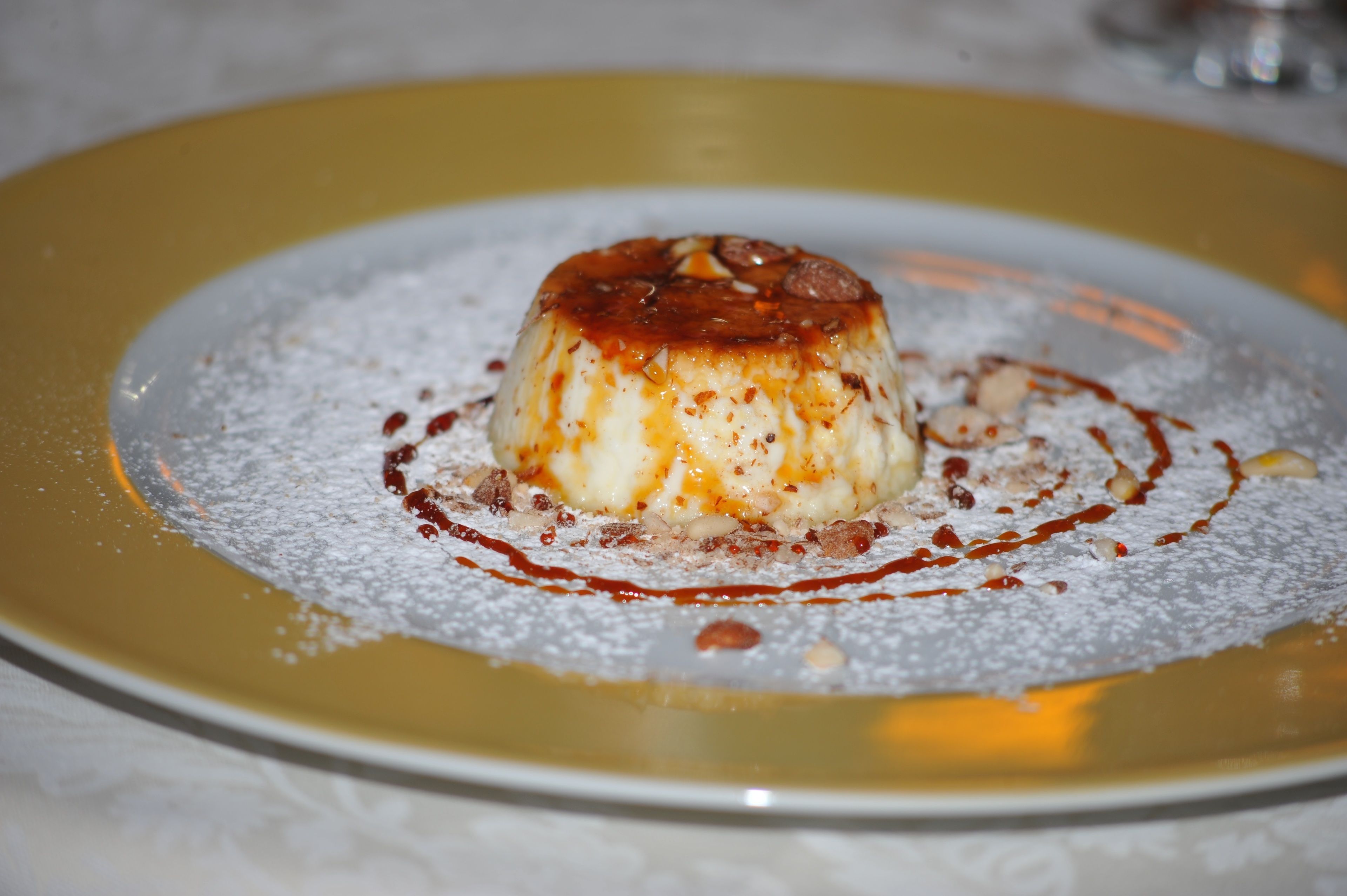 A dessert on a plate with powdered sugar and chocolate drizzle.