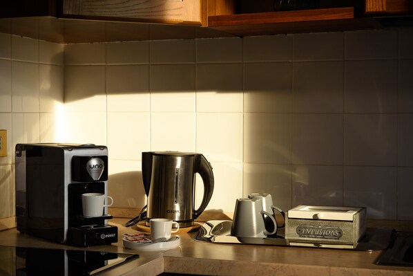 Una cocina con cafetera, hervidor y una caja etiquetada como 'Infusions'.
