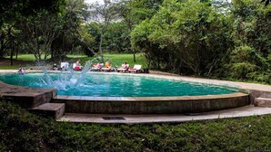 Una piscina al aire libre, sillones reclinables de piscina