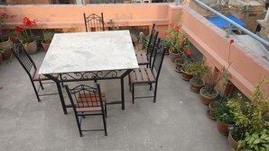 A terrace with a marble table and metal chairs, surrounded by potted plants. - Om Pension Guest House (Lalitpur)