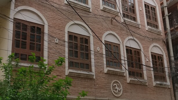 A multi-story building with arched windows and a sign indicating a pension house. - Om Pension Guest House (Lalitpur)