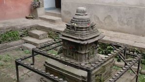 A stone structure with a tiered base and a central pillar, surrounded by a metal railing. - Om Pension Guest House (Lalitpur)