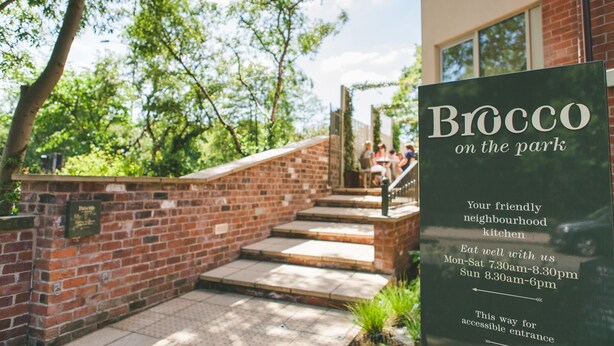Un cartel que indica "Brocco on the Park" con una escalera que lleva a un edificio de ladrillo.