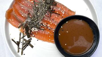 A plate with salmon and a bowl of sauce.