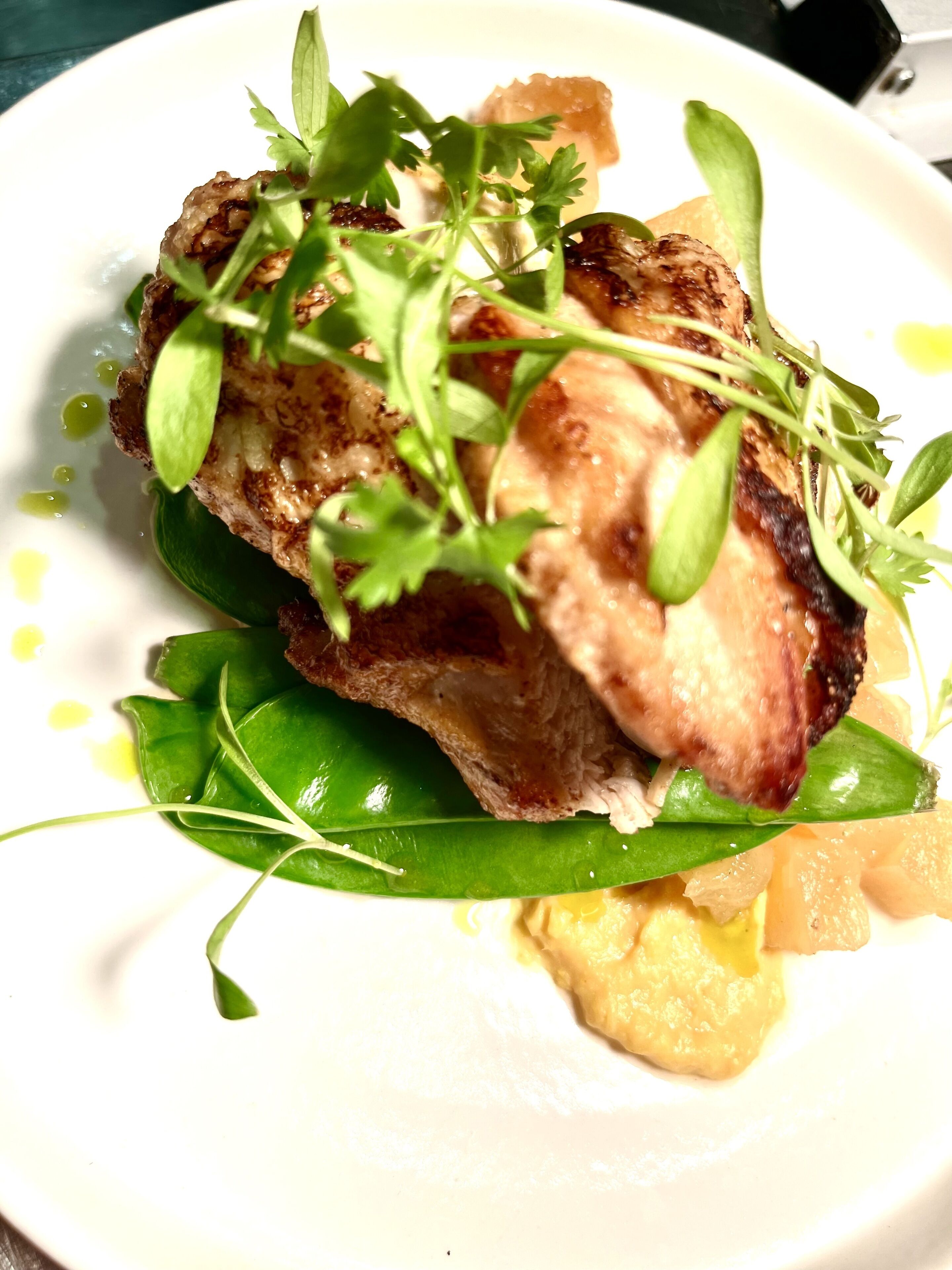Un plato con carne a la parrilla, verduras verdes y salsa cremosa.
