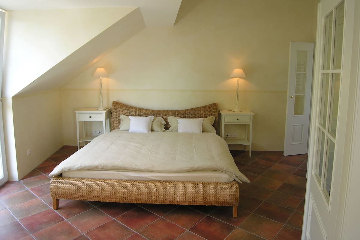 Une chambre à coucher avec un grand lit, deux tables de chevet et un plafond en pente.