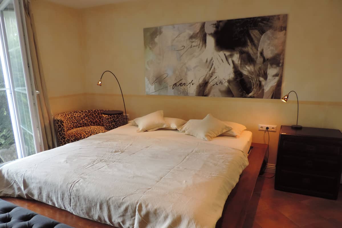 Une chambre moderne avec un grand lit, un fauteuil à motifs léopard et un grand tableau abstrait accroché au mur.