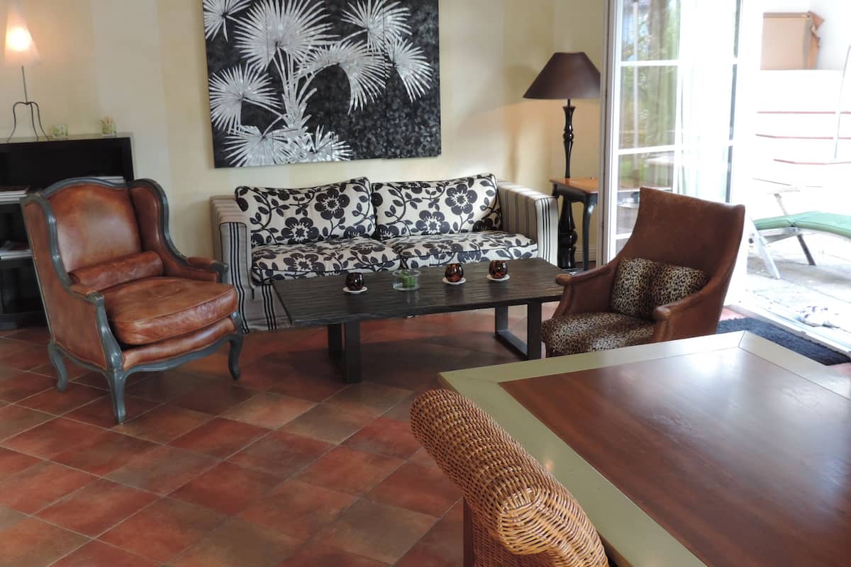 Un salon comprenant un canapé, deux fauteuils, une table basse et un tableau accroché au mur.