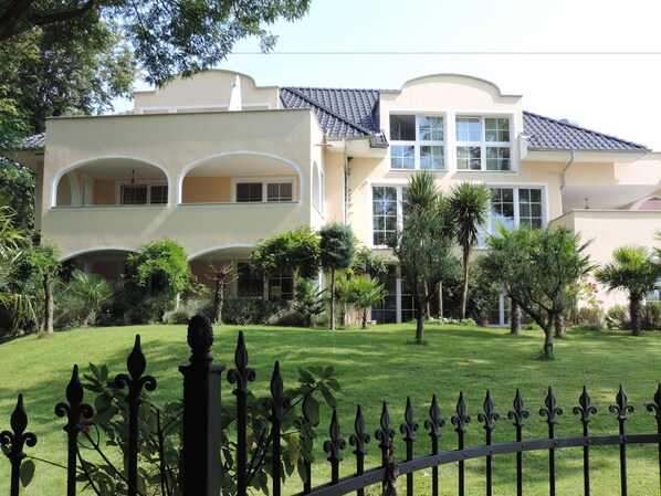 A two-story building with a balcony and a well-maintained lawn. - Park-Villa (Kressbronn)