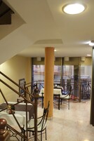 Vestíbulo de hotel con una escalera, un pilar grande y vista al exterior a través de un puerta de vidrio.
