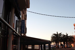 A hotel with a sign reading "HOTEL" and a covered outdoor area with palm trees. - Hotel del Port (L'Ametlla de Mar)