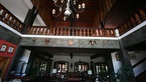 Un'ampia hall con soffitto alto, travi in legno e un lampadario. Sono presenti diverse zone relax e una reception.