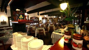 Un ristorante con diversi tavoli, una zona bar e varie disposizioni di tavola con piatti e posate.