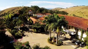 Una proprietà rurale con un cortile centrale, circondata da vegetazione lussureggiante e dolci colline.