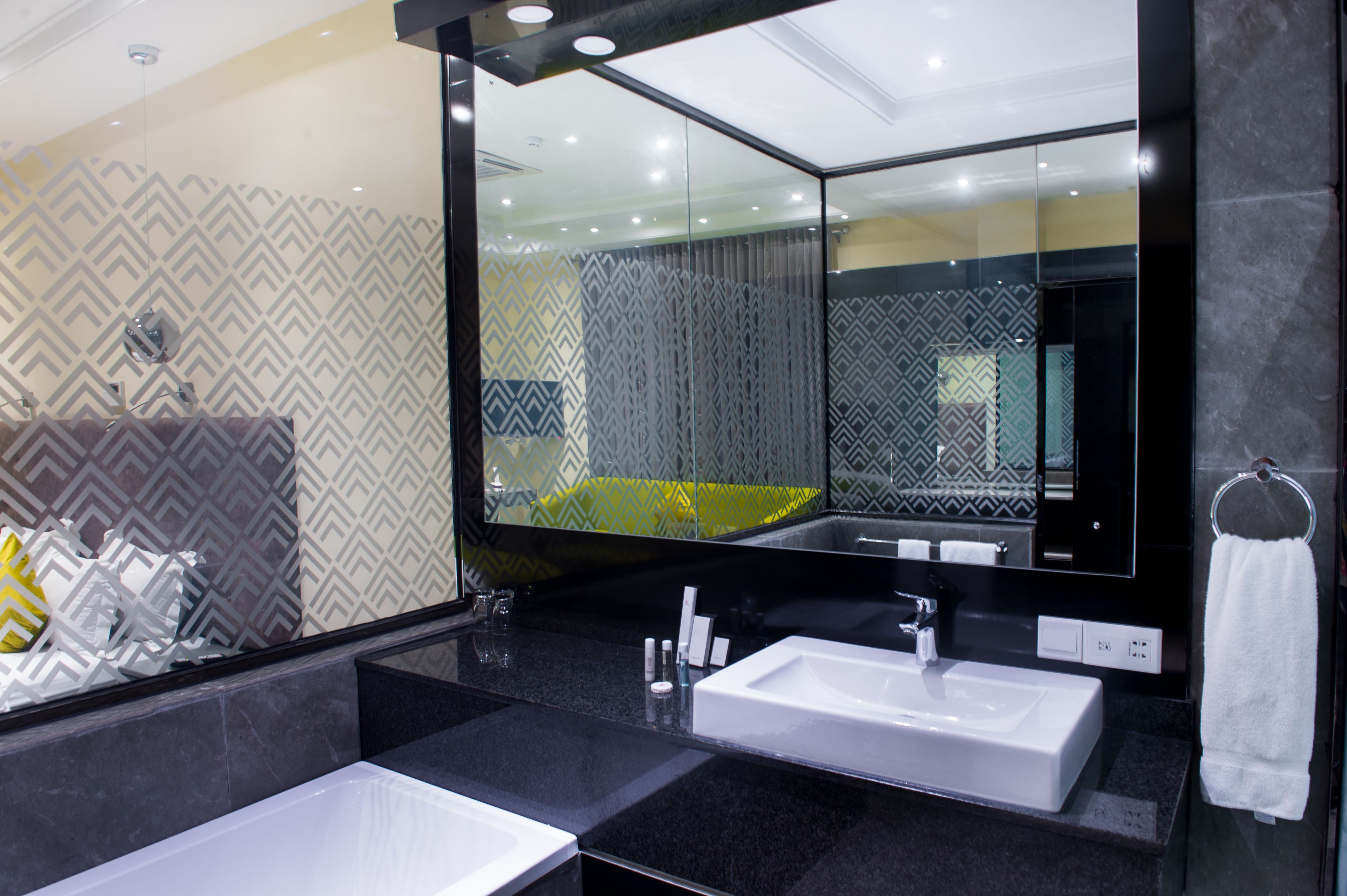 Un baño moderno con dos lavamanos, un espejo grande y papel tapiz estampado.