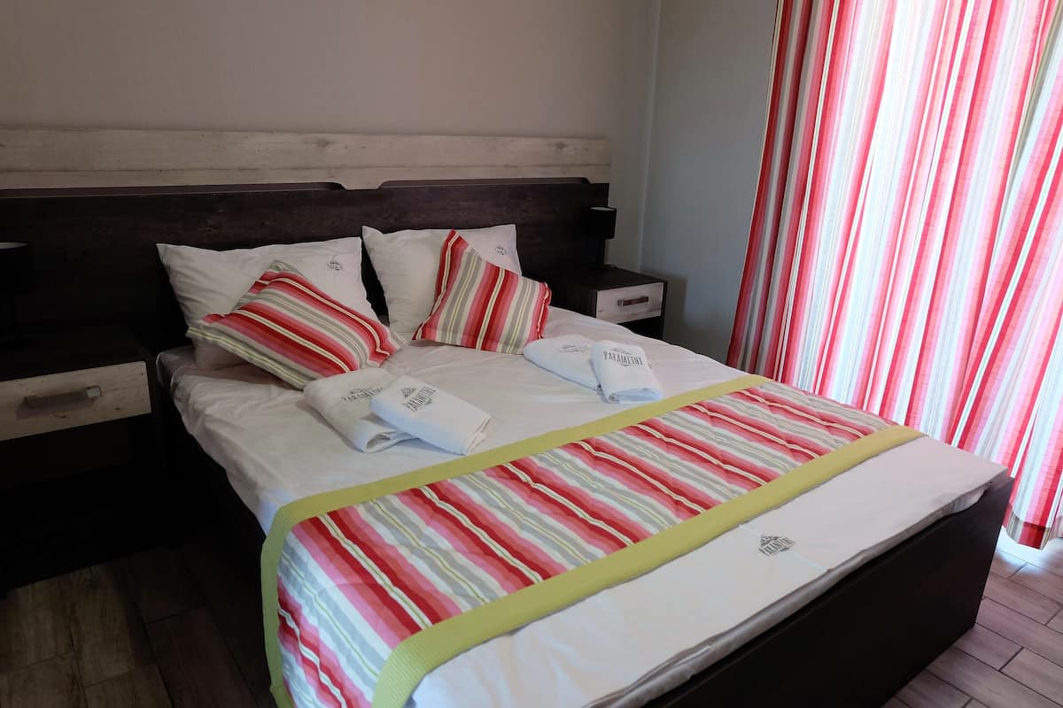 A neatly made bed with striped bedding, pillows, and a folded towel.