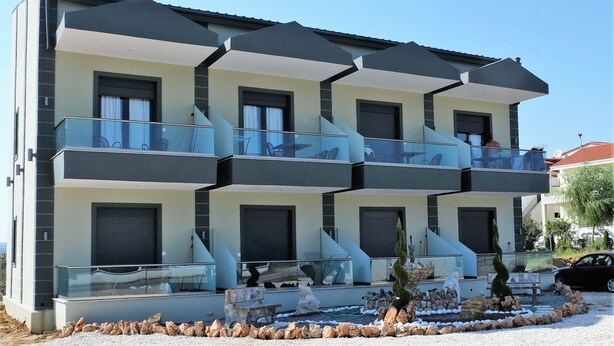 Un immeuble moderne à plusieurs étages, doté de balcons, de grandes fenêtres et d’un jardin aménagé.