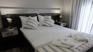 Une chambre d’hôtel avec un grand lit, deux tables de chevet et une petite table de nuit.