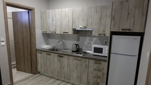 Une cuisine équipée de meubles en bois, d’un four à micro-ondes, d’une bouilloire et d’un réfrigérateur.