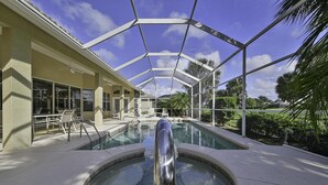 Une piscine couverte offrant une vue dégagée sur le ciel, entourée de palmiers et bordée d’un bâtiment doté de grandes fenêtres.
