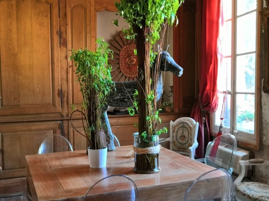 A wooden dining table with two potted plants, a decorative mirror, and a vintage chair.
