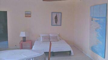 A bedroom with two beds, a small table with a lamp, and a large painting of a beach scene.