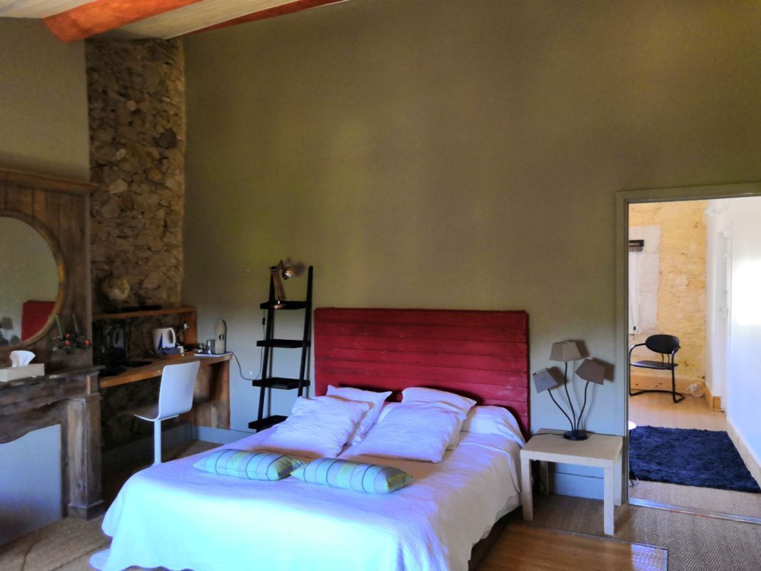 Quarto com cama, escrivaninha, cadeira, mesa de cabeceira e espelho.