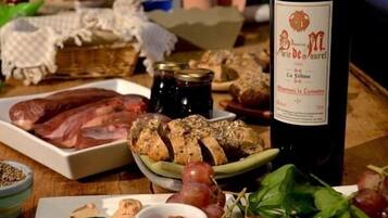 A table with various food items including sliced bread, grapes, and a bottle of wine.