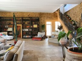 Un salón espacioso con una amplia estantería, un sofá cómodo y una escalera que sube a un nivel superior.