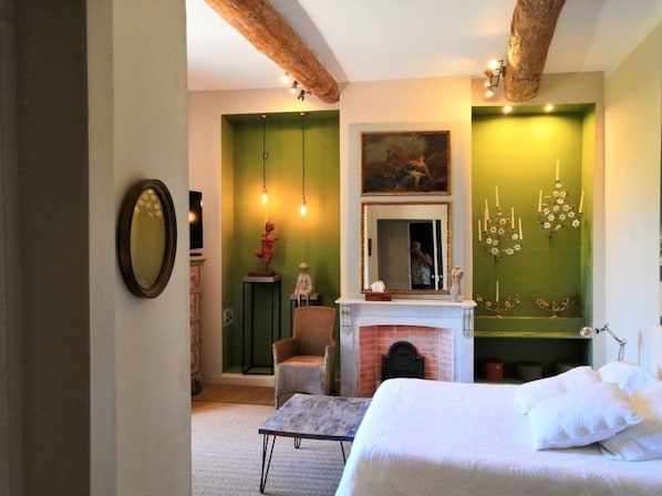 Quarto com cama, lareira, poltrona e espelho.