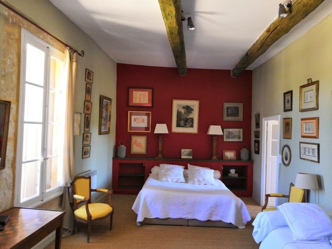 A bedroom with a bed, a chair, a desk, and a window.