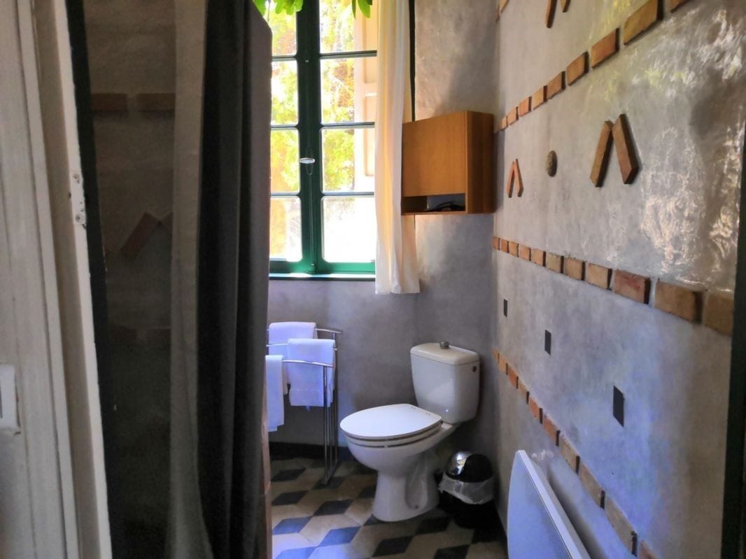 A bathroom with a checkered floor, a toilet, a sink, and a window.