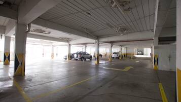 A multi-level parking garage with concrete pillars, yellow directional arrows, and several parked cars.